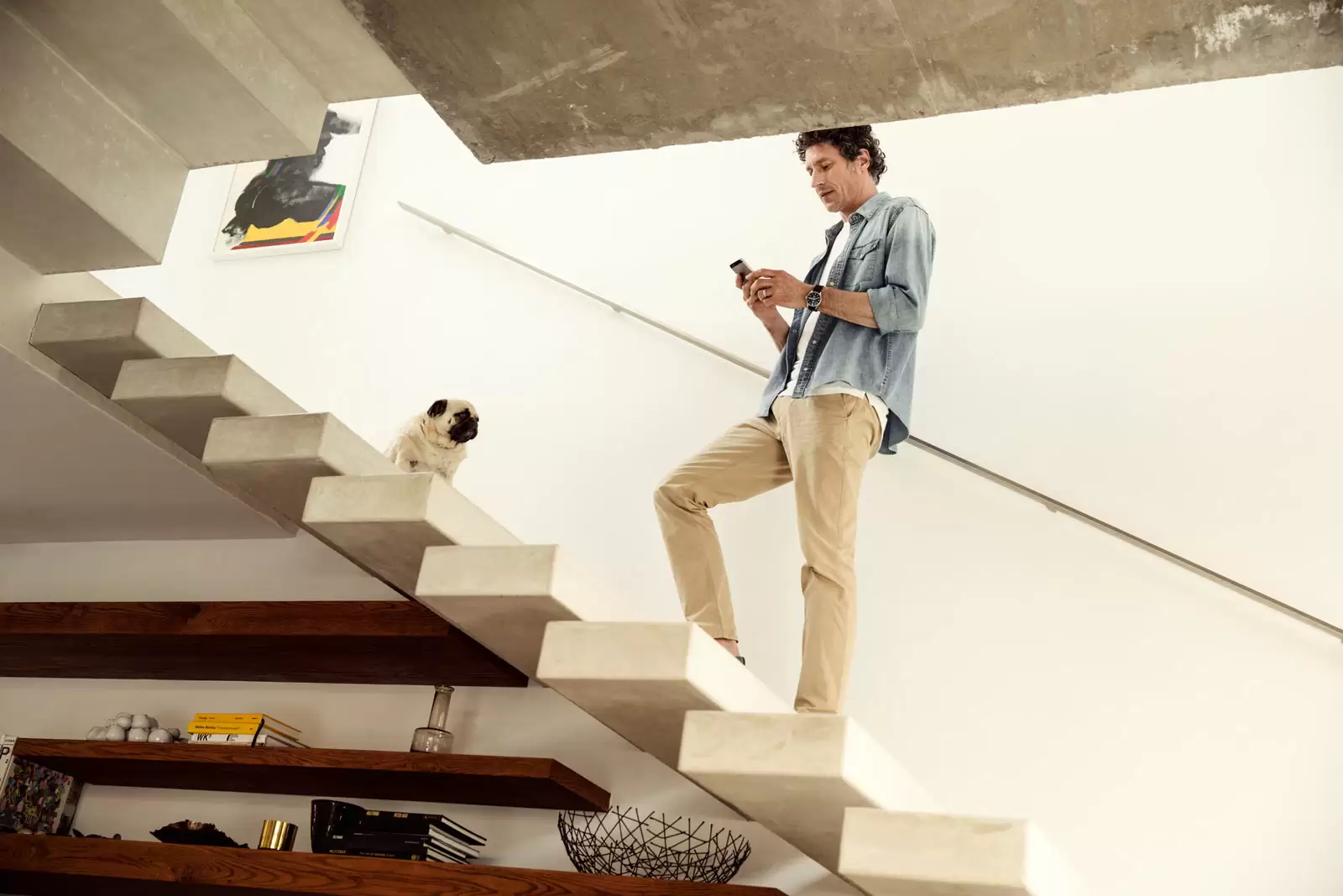 Mann steht auf Treppe und checkt auf dem Smartphone seinen Sparplan
