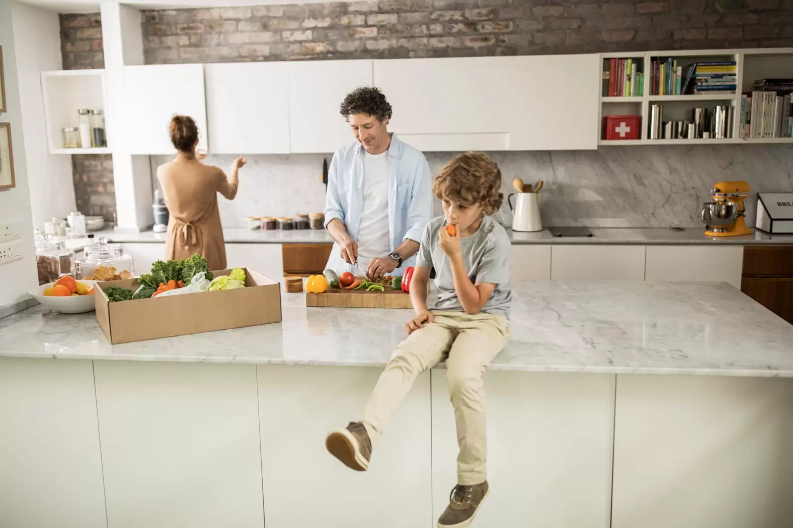 Familie in Küche ist mit der Hausratversicherung abgesichert.