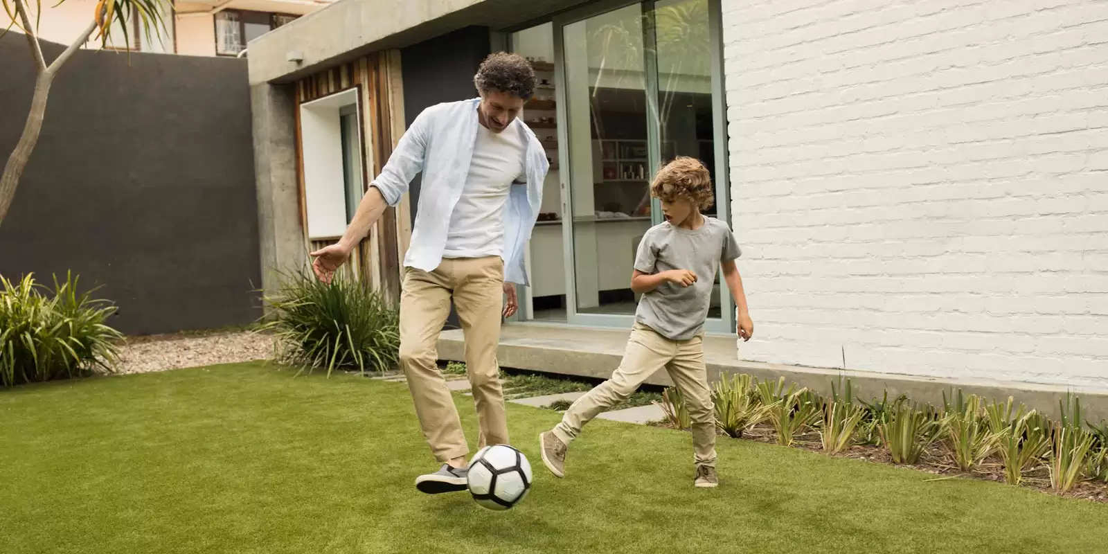 Mann spielt mit seinem Sohn Fußball und denkt über den Rahmenkredit nach