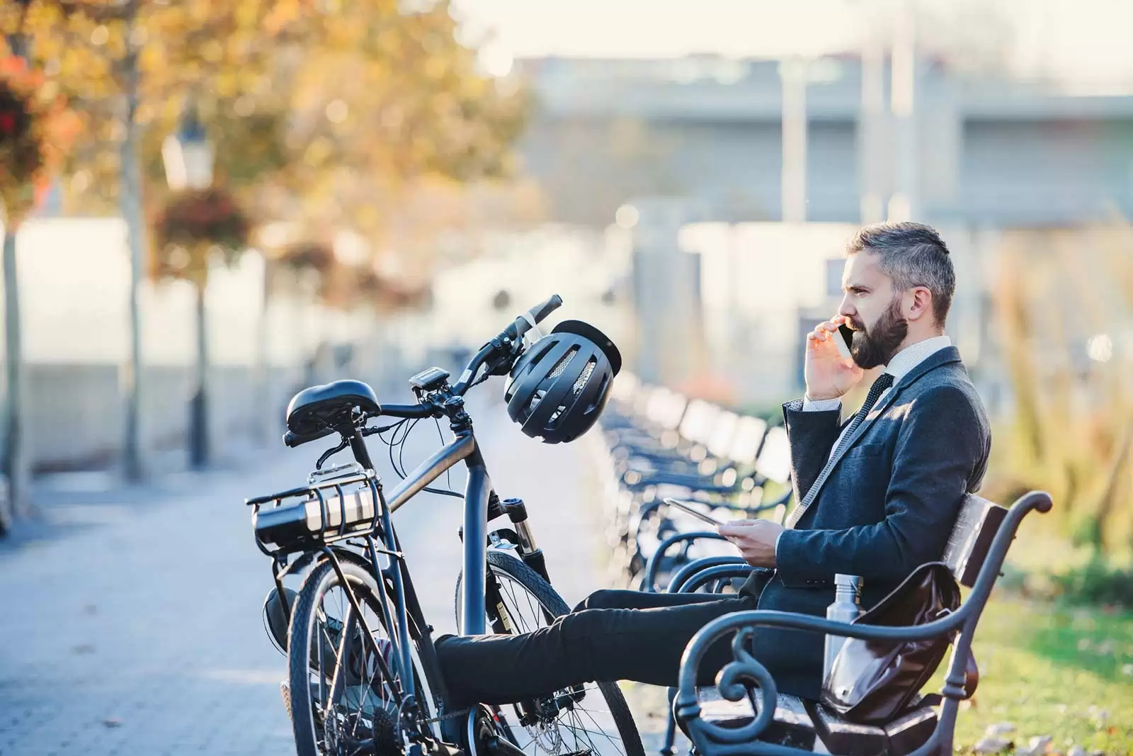 Mann sitzt vor einem E-Bike auf einer Bank
