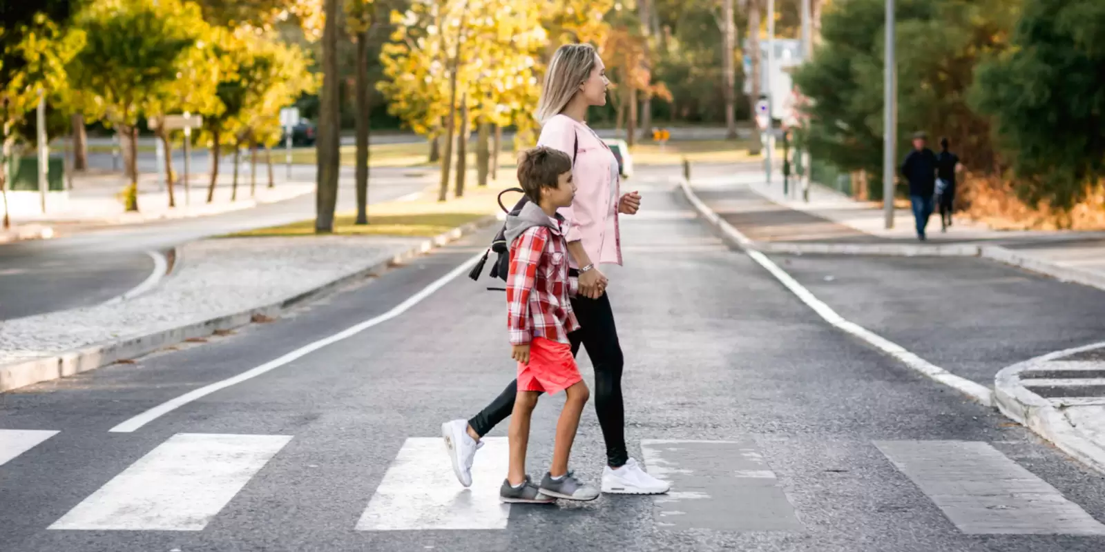 Mutter und Sohn gehen über Fußgängerüberweg