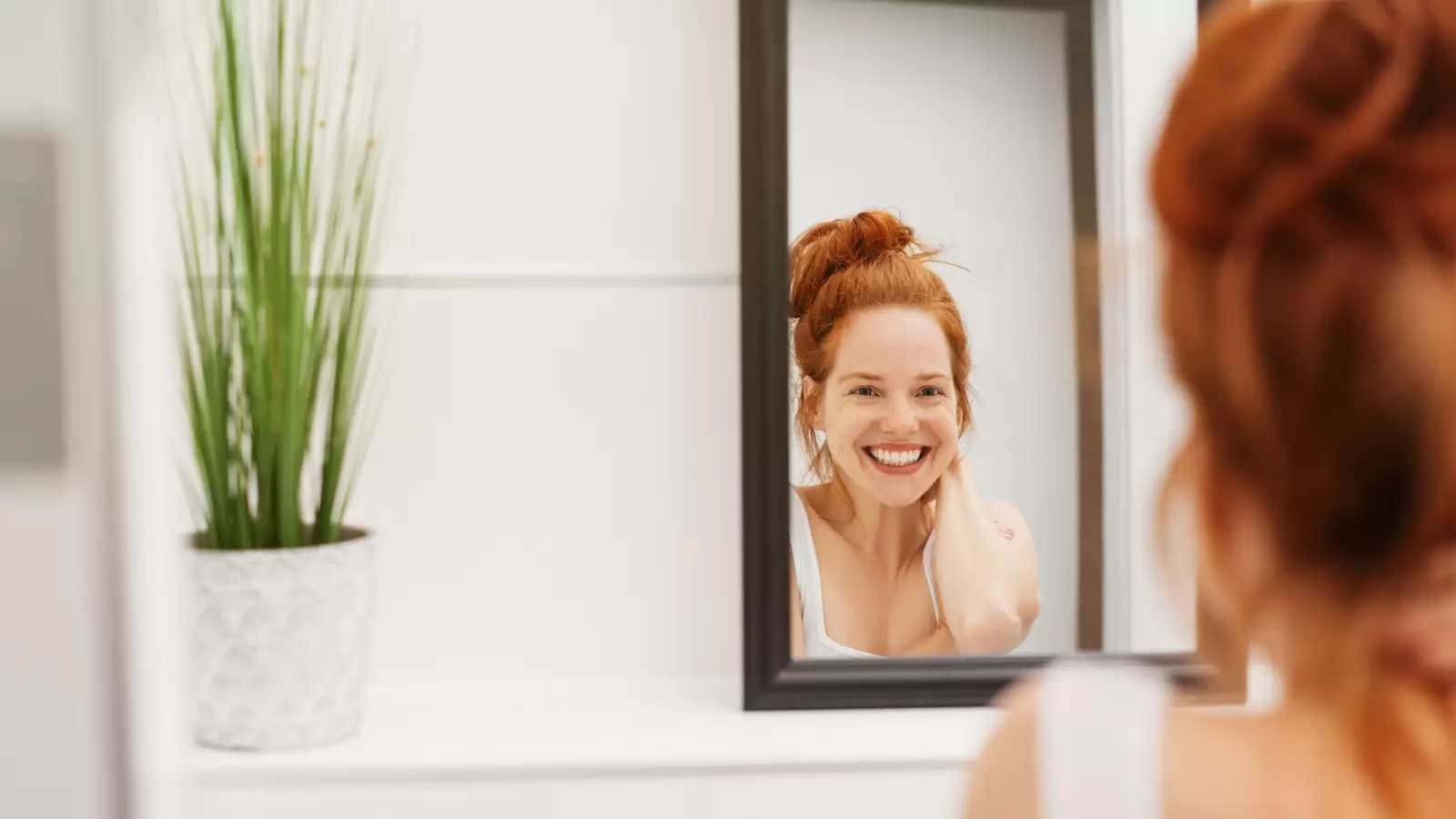Frau bewundert ihre schönen Zähne im Spiegel