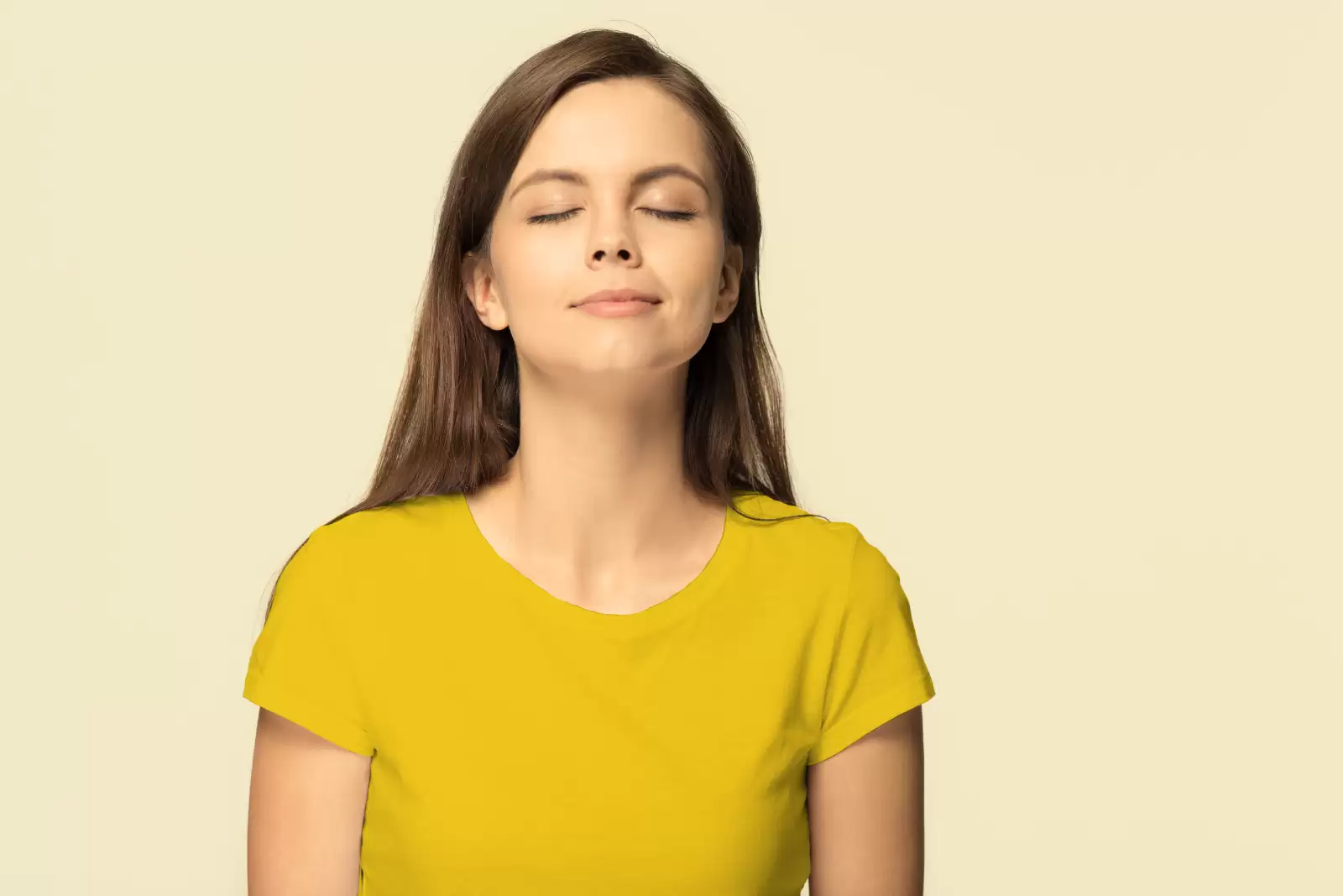 Eine Frau mit gelben T-Shirt atmet durch die Nase ein.